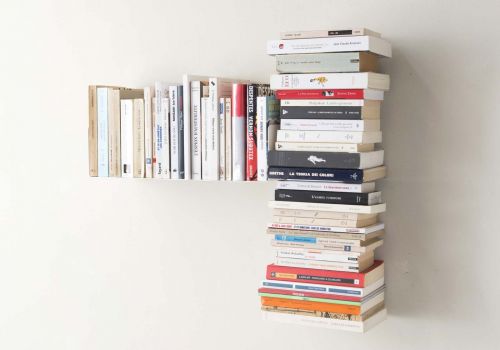 bibliothèque murale gauche installée dans un salon moderne avec des livres empilés